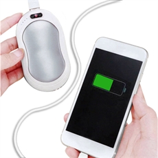 Oval powerbank i handen, laddar telefon via USB; telefonen visar laddningssymbol.