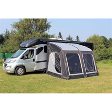 Förtält med genomskinliga fönster och sidodörrar, fäst vid campervan på gräs med träd bakom.