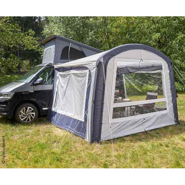 Förtält med fönster fäst vid VW-camper på gräs, säkrat med rep för stabilitet.