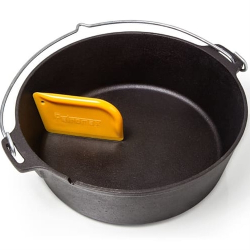 Gul Petromax skrapa med tandade kanter i en mörk gryta med metallhandtag.